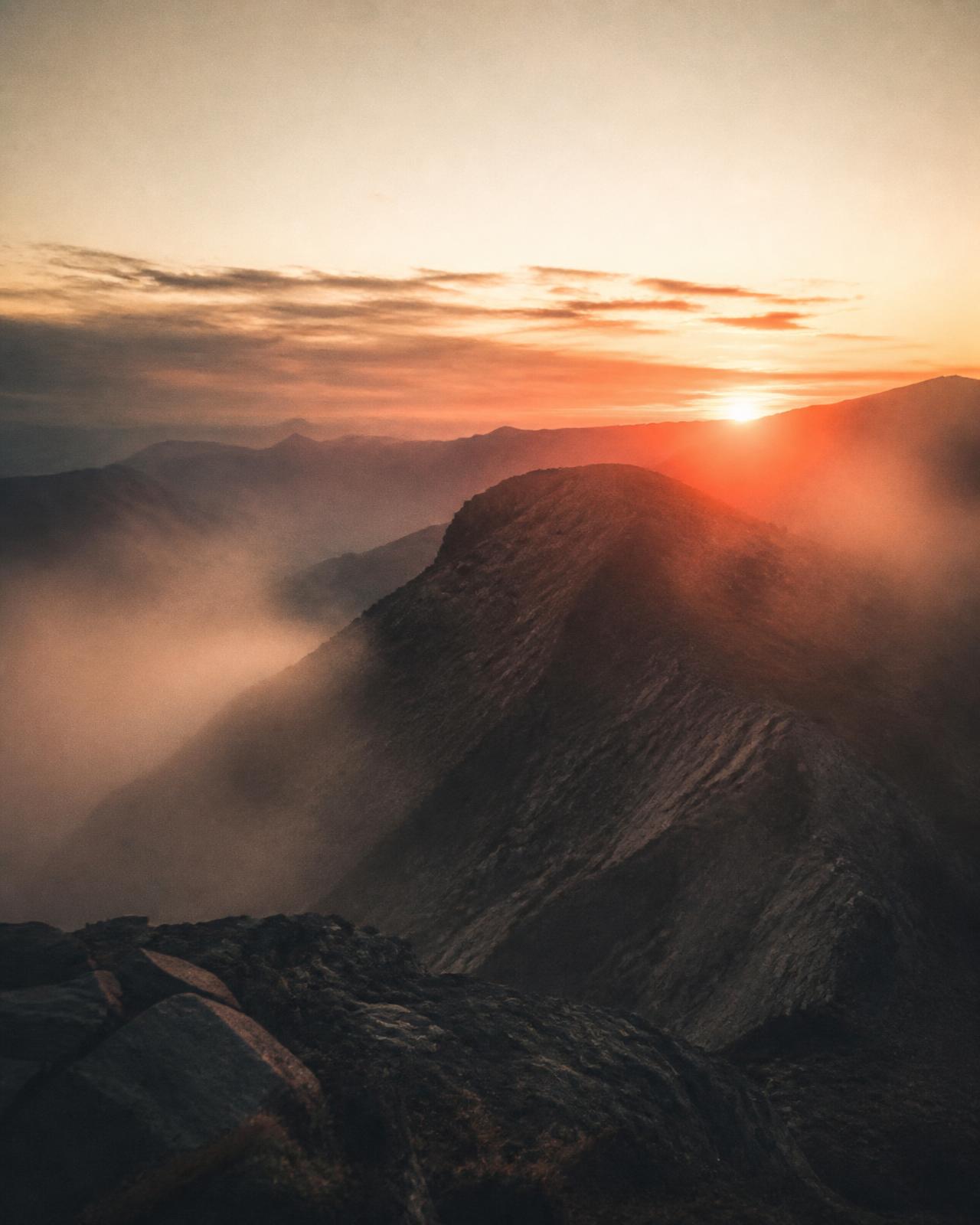 Amanhecer sobre uma cordilheira, com a primeira luz rompendo o horizonte